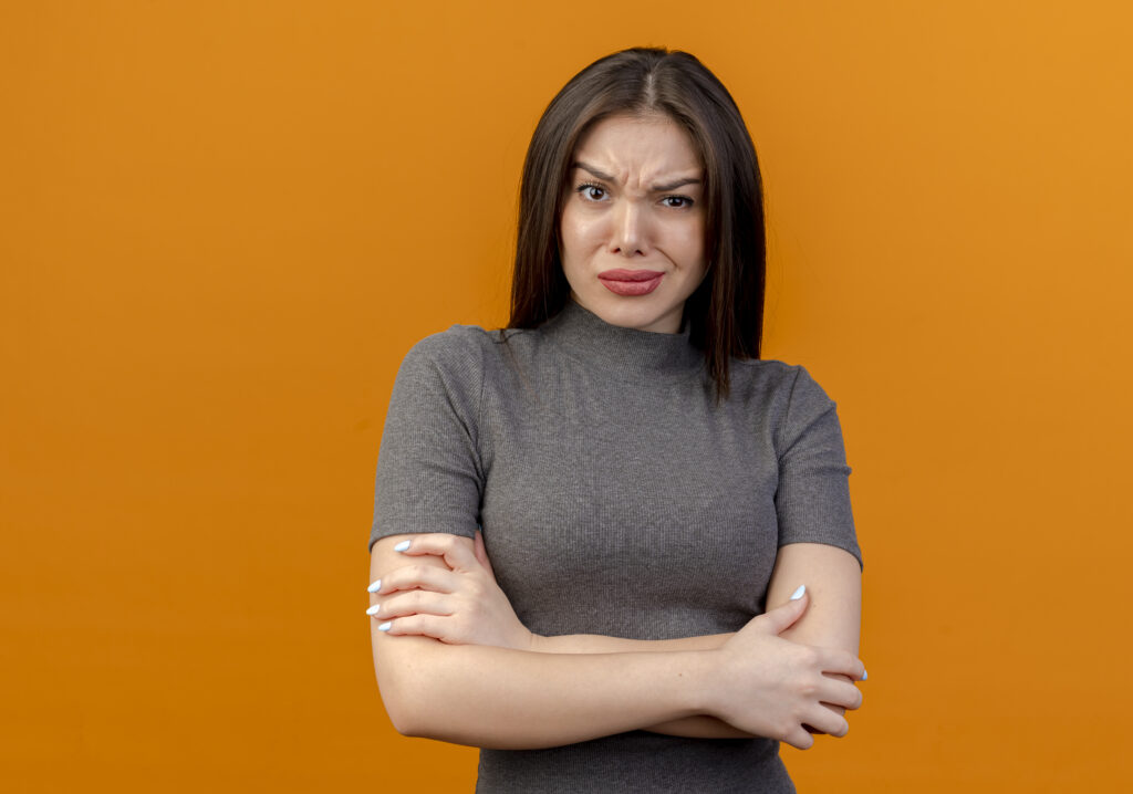 frowning young pretty woman standing with closed posture isolated on orange background with copy space Propriétaire qui refuse de négocier le prix de vente